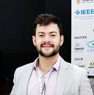 Homem sorrindo em frente a um poster acadêmico